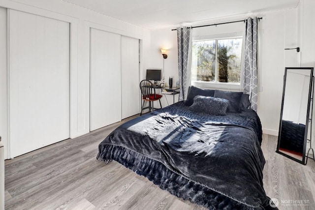 bedroom with two closets and wood finished floors