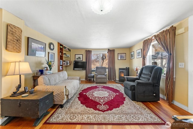 living area featuring a fireplace, baseboards, and wood finished floors