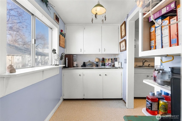 kitchen featuring white cabinets, baseboards, and a sink