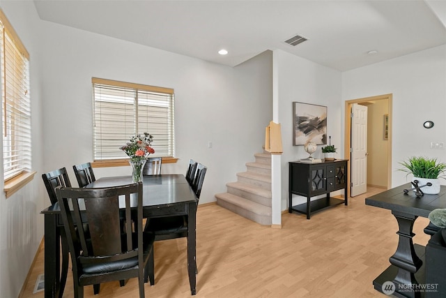 dining area with a healthy amount of sunlight, visible vents, light wood finished floors, and stairs