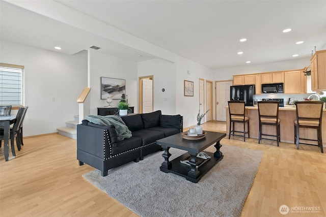 living area with light wood-type flooring, visible vents, stairway, and recessed lighting