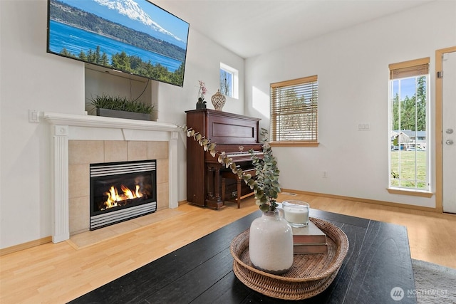 living area with light wood-style flooring, a fireplace, and baseboards