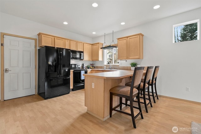 kitchen with light wood-style flooring, light brown cabinets, a sink, a peninsula, and black appliances