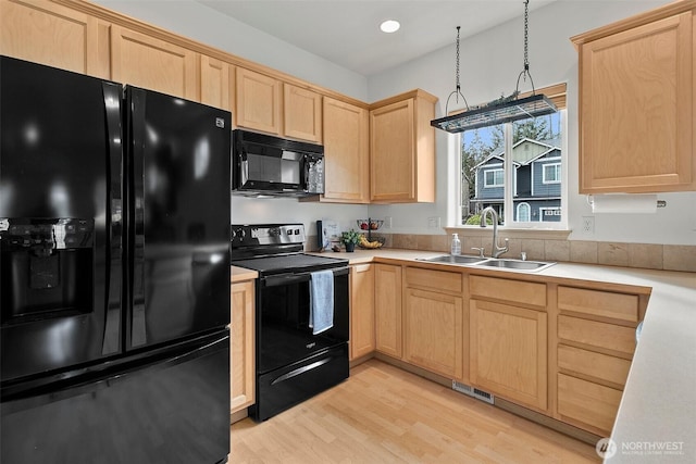 kitchen with light countertops, light wood-style flooring, light brown cabinets, a sink, and black appliances