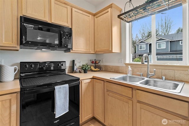 kitchen with black appliances, light brown cabinetry, a sink, and light countertops