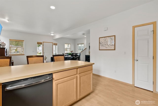 kitchen with light wood-style flooring, open floor plan, stainless steel dishwasher, and light brown cabinetry