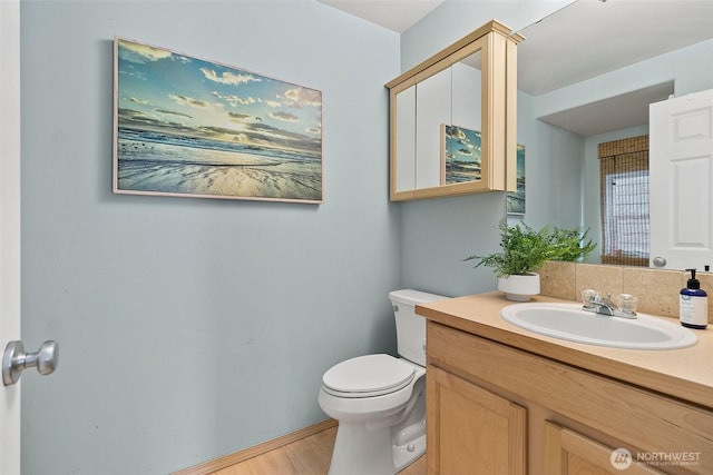 half bathroom featuring vanity, toilet, and wood finished floors