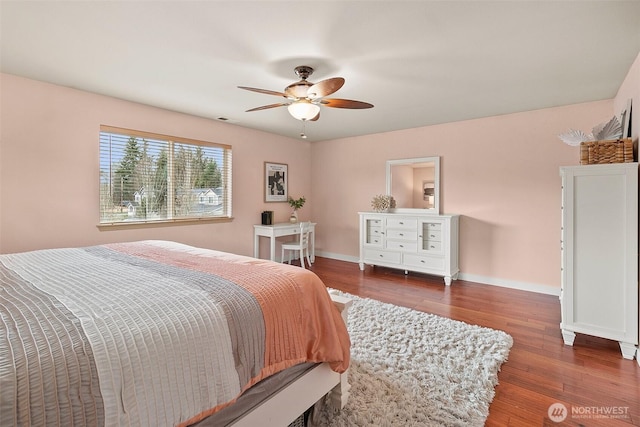 bedroom with a ceiling fan, visible vents, baseboards, and wood finished floors