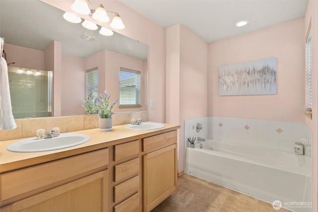 full bathroom with a bath, double vanity, visible vents, and a sink