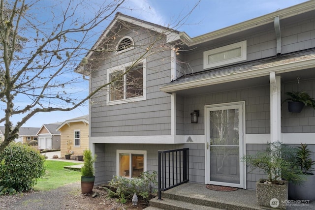 view of exterior entry with roof with shingles