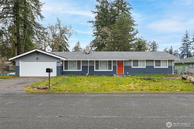 ranch-style home featuring aphalt driveway, a chimney, an attached garage, and a front yard