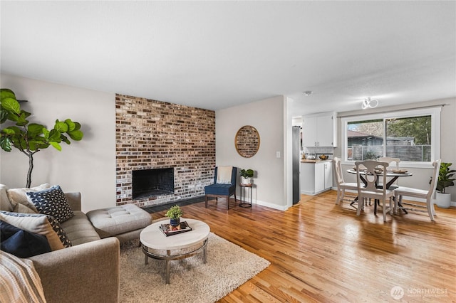 living area featuring light wood-style floors, a fireplace, and baseboards