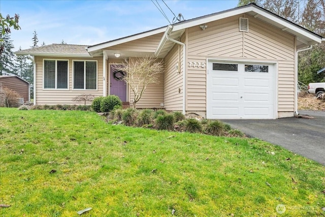 single story home with aphalt driveway, a garage, and a front yard