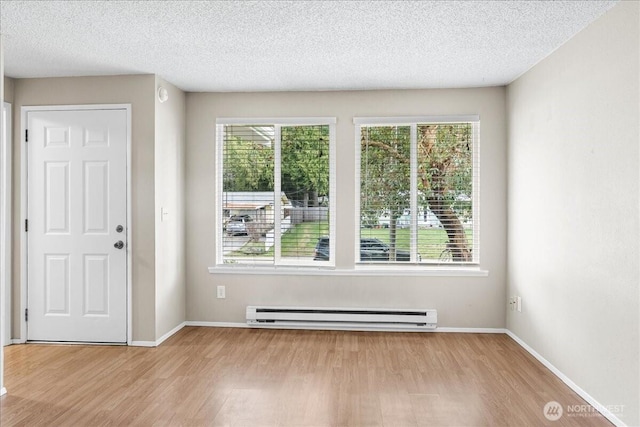 foyer featuring baseboard heating, baseboards, and wood finished floors