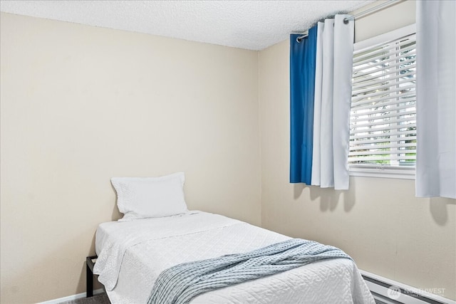 bedroom with a textured ceiling, a baseboard heating unit, and baseboards