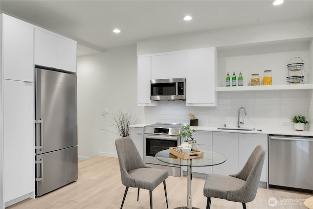 kitchen with appliances with stainless steel finishes, modern cabinets, a sink, and tasteful backsplash