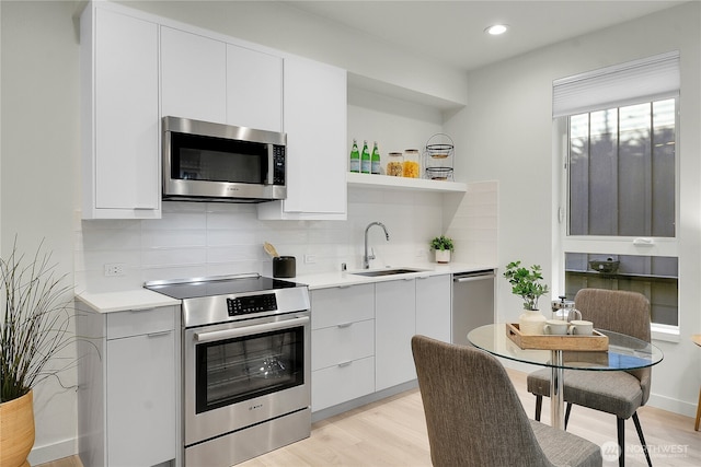 kitchen featuring stainless steel appliances, modern cabinets, a sink, and light countertops