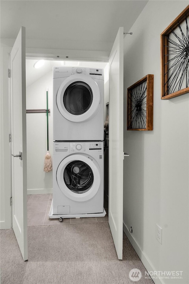 clothes washing area with laundry area, carpet floors, stacked washer and clothes dryer, and baseboards