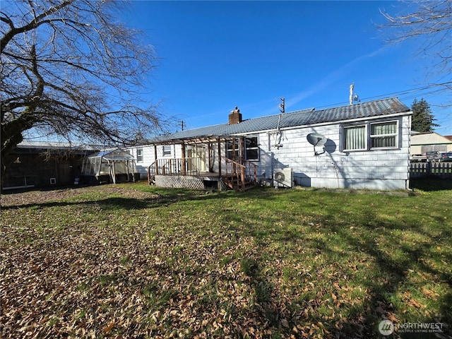 back of property featuring a yard, a chimney, and a wooden deck