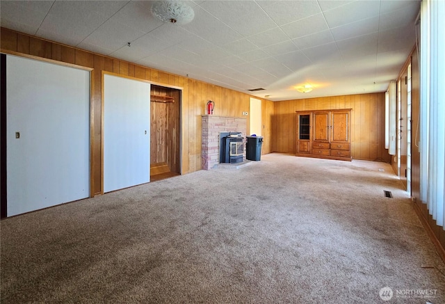 unfurnished living room featuring carpet floors, visible vents, and wood walls