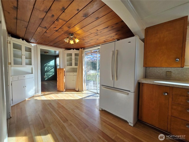 kitchen featuring wooden ceiling, light wood-style flooring, light countertops, freestanding refrigerator, and brown cabinetry