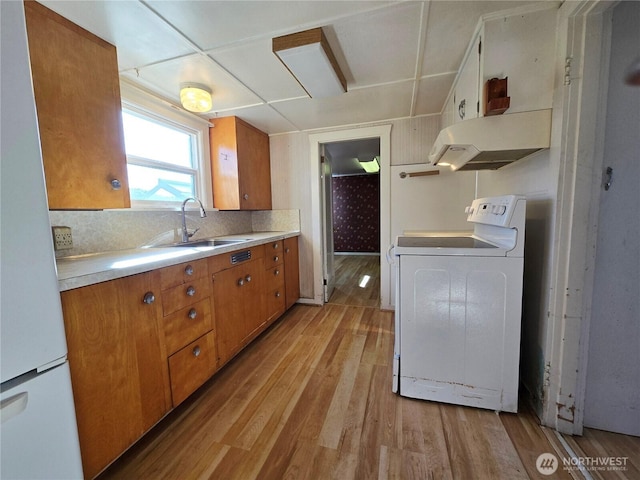 kitchen with brown cabinetry, light wood-type flooring, and white appliances