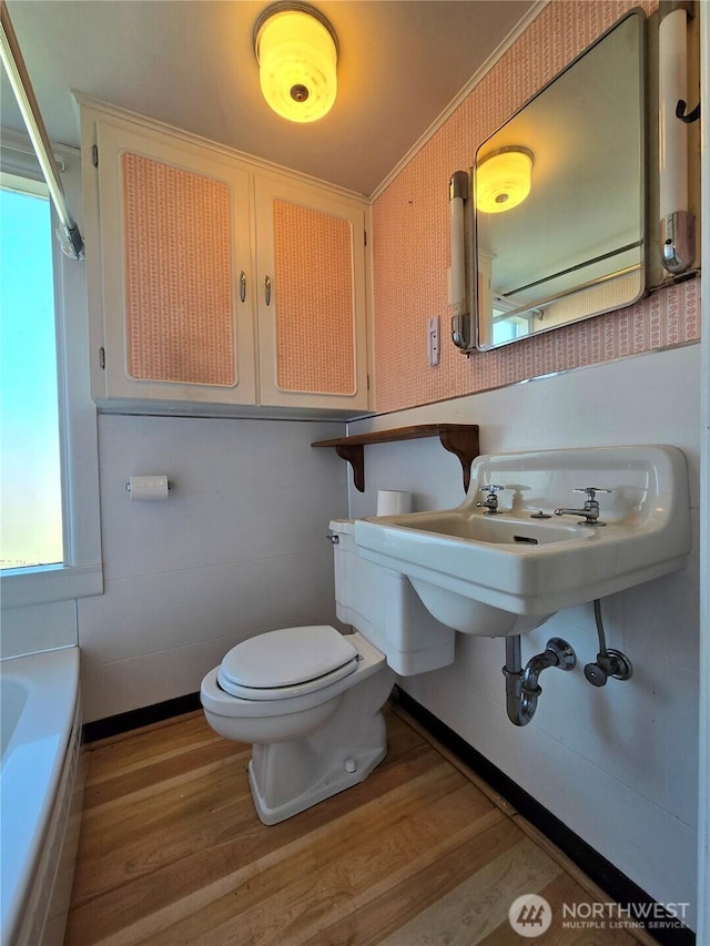 full bathroom with a bath, toilet, and wood finished floors