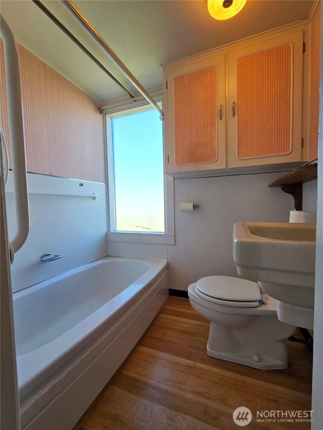 bathroom featuring toilet, wood finished floors, and a washtub