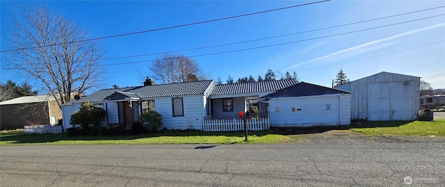 view of front of house featuring a chimney, a front yard, a garage, driveway, and a tiled roof