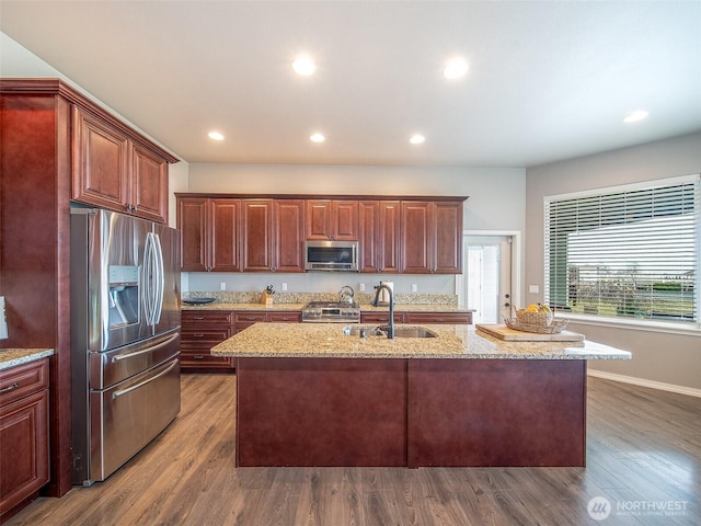 kitchen featuring a center island with sink, wood finished floors, stainless steel appliances, a sink, and recessed lighting