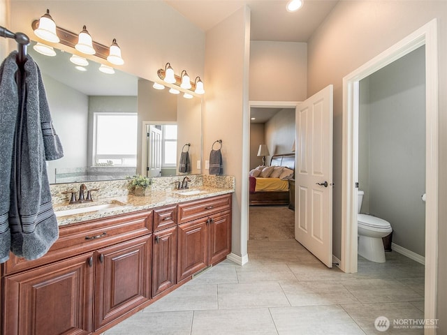 bathroom with double vanity, a sink, toilet, and connected bathroom