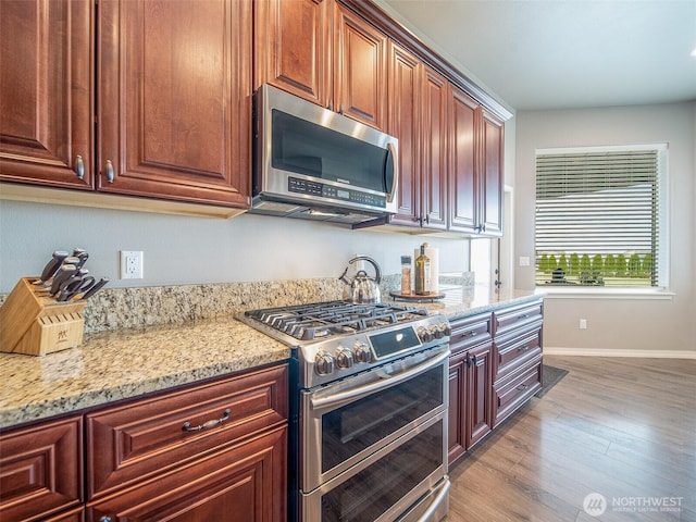 kitchen featuring light stone countertops, light wood-style floors, baseboards, and stainless steel appliances