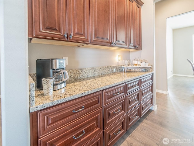 kitchen featuring light wood-style floors, baseboards, and light stone countertops