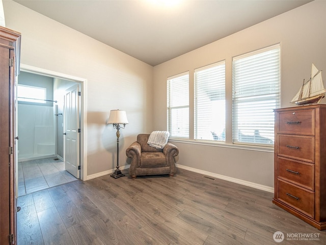 sitting room with dark wood-type flooring, visible vents, and baseboards