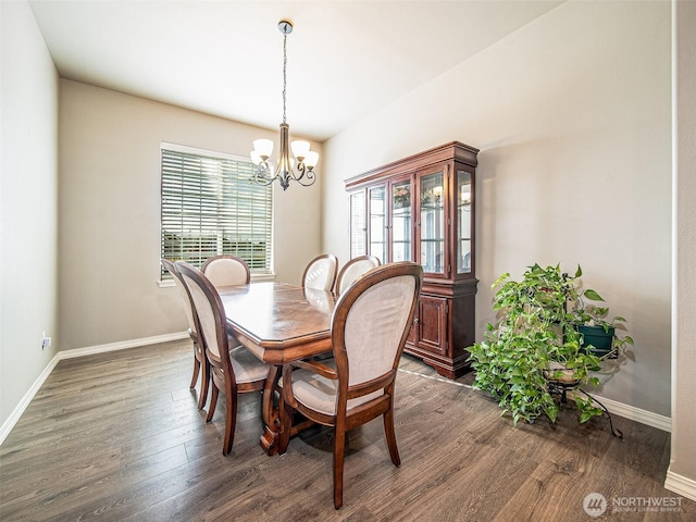 dining space with baseboards, an inviting chandelier, and wood finished floors