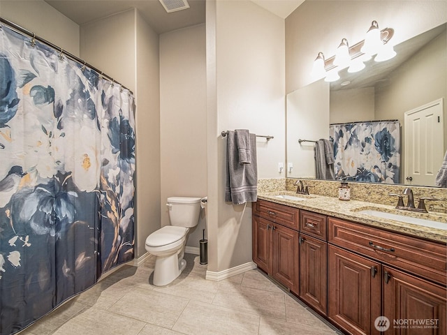 bathroom with toilet, double vanity, baseboards, and a sink