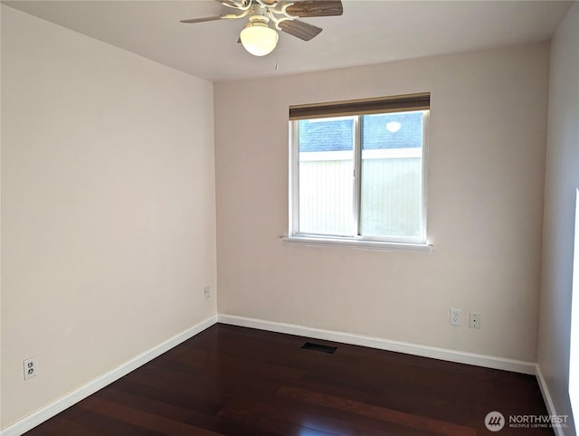 spare room with dark wood-style floors, visible vents, ceiling fan, and baseboards