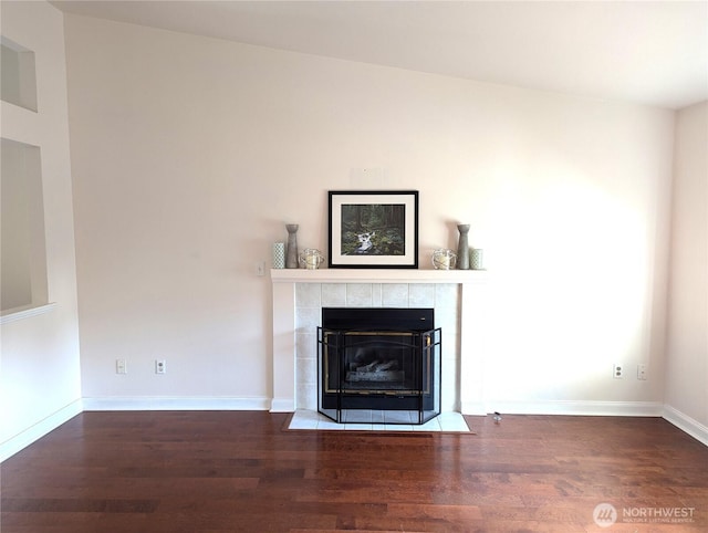 unfurnished living room featuring baseboards, a tiled fireplace, and wood finished floors