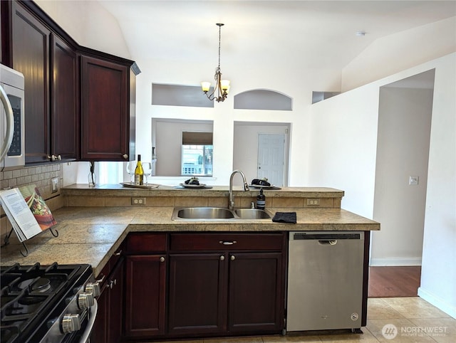 kitchen with a peninsula, a sink, vaulted ceiling, hanging light fixtures, and appliances with stainless steel finishes