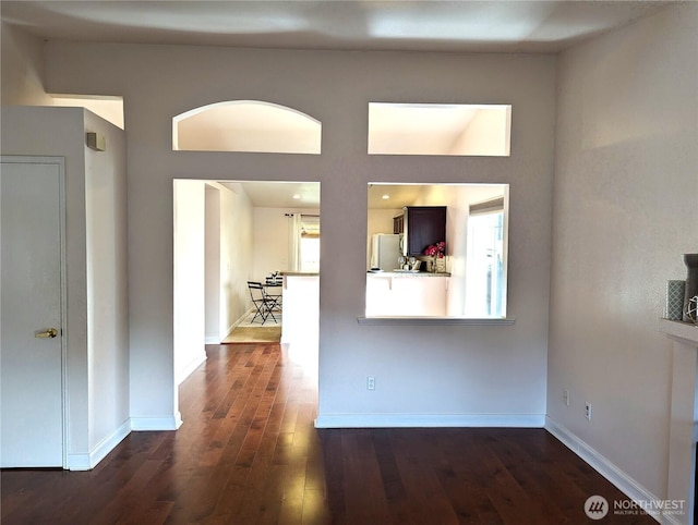 unfurnished room featuring dark wood-type flooring and baseboards