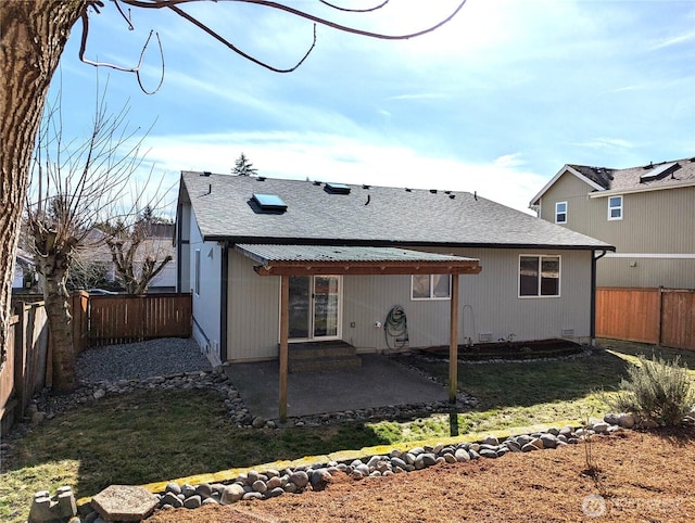 back of property with a yard, a patio, a shingled roof, and a fenced backyard