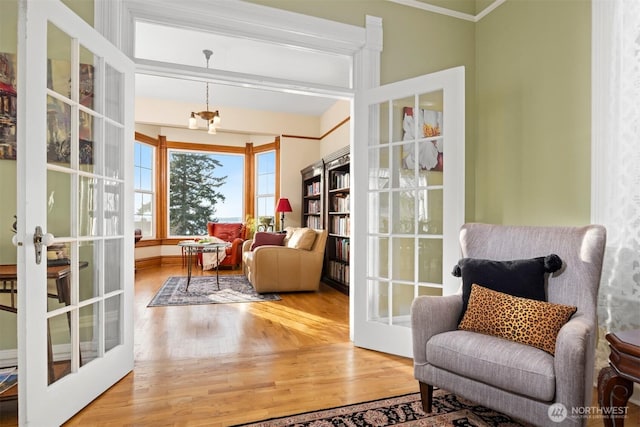 sitting room featuring a chandelier, french doors, wood finished floors, and beam ceiling