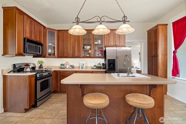 kitchen featuring light countertops, appliances with stainless steel finishes, a sink, and glass insert cabinets