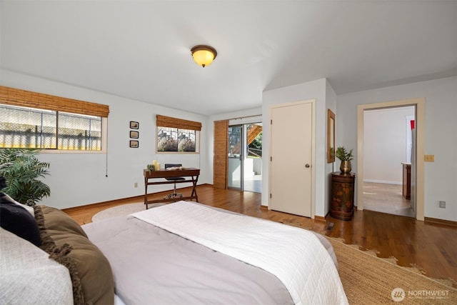 bedroom with multiple windows, baseboards, and wood finished floors