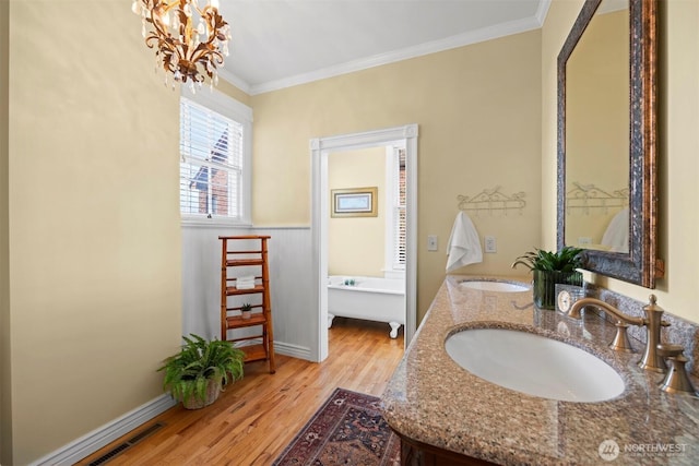 bathroom featuring wood finished floors, a sink, visible vents, and crown molding