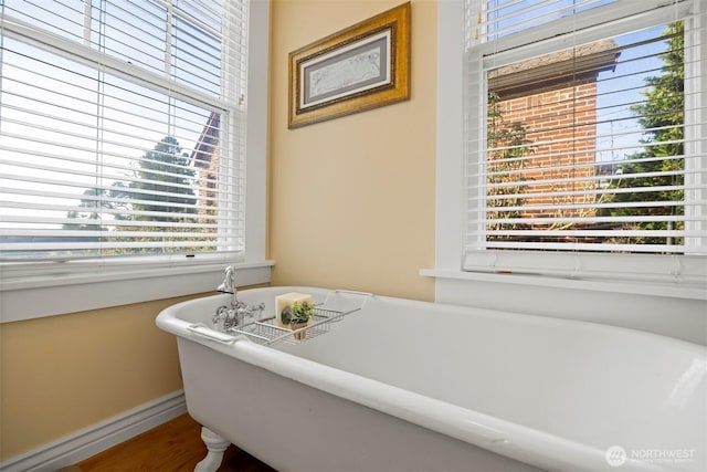 full bath featuring a freestanding bath, baseboards, and wood finished floors