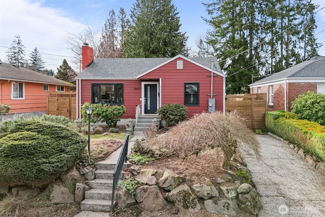 bungalow with roof with shingles, fence, and a chimney