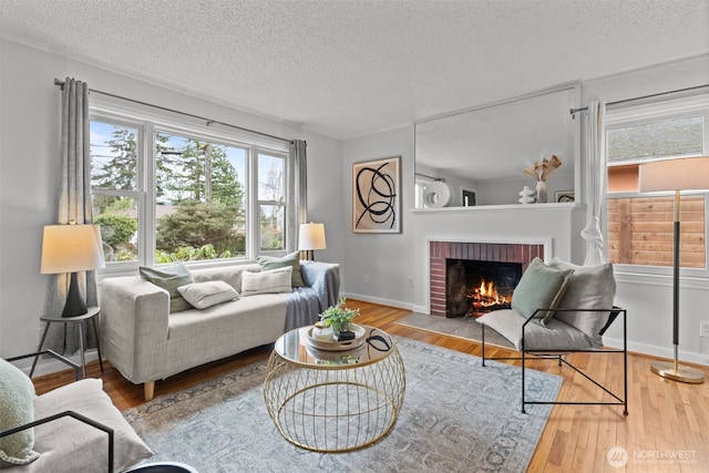 living room with a textured ceiling, a fireplace, baseboards, and hardwood / wood-style floors