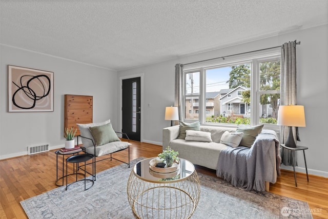 living area featuring visible vents, baseboards, and wood finished floors