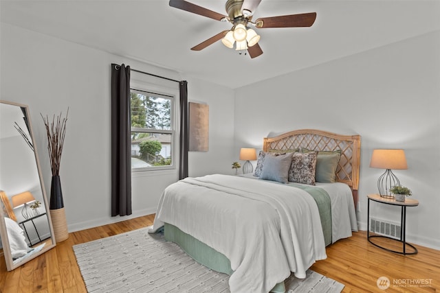 bedroom featuring baseboards, visible vents, a ceiling fan, and light wood-style floors